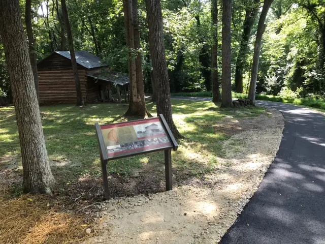 Old tobacco barn behind explanatory plaque beside trail in the park.