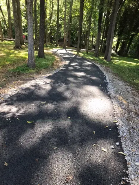 View of paved trail leading down hill through the trees in the park.